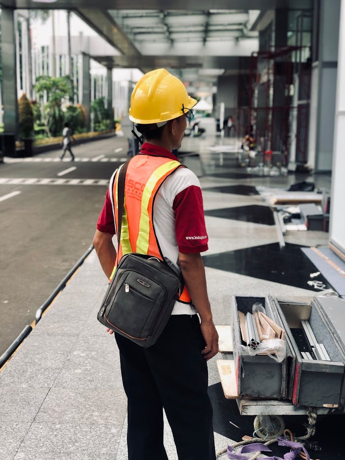 Construction worker standing on Jakarta street, wearing safety gear and helmet.