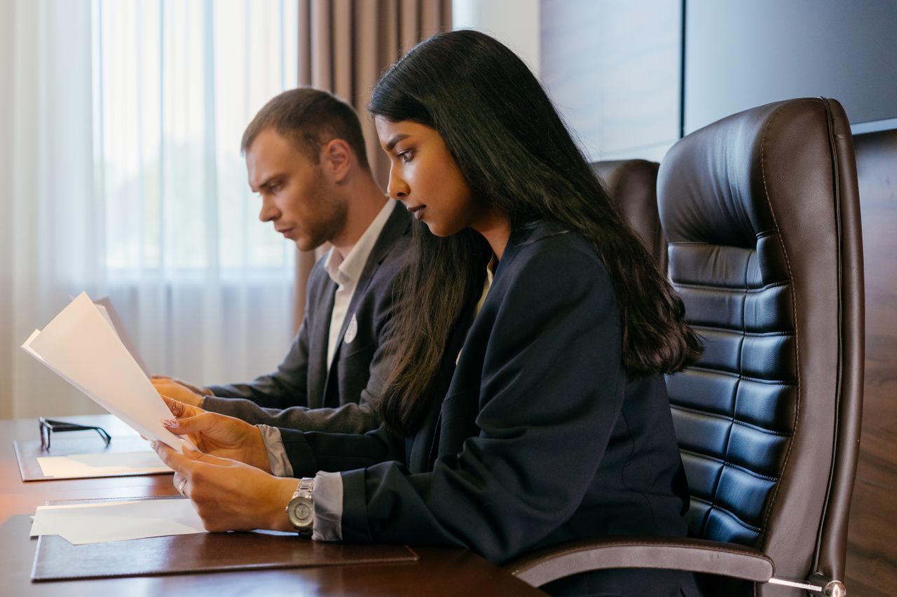 Two professionals reviewing documents in an office setting, showcasing teamwork and diversity.